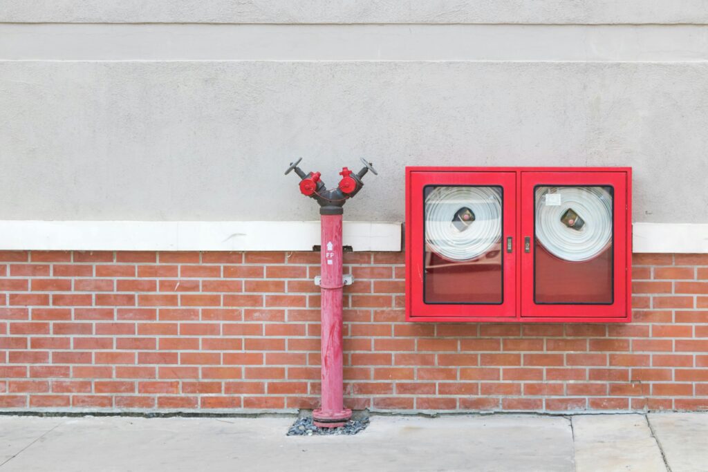 pexels-photo-13060858-13060858 Outdoor fire hydrant and hoses against a brick wall, emphasizing fire safety.
