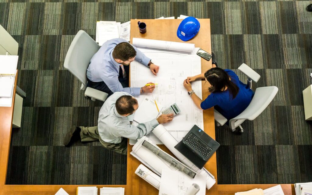 pexels-photo-416405 Top view of a team working on construction plans in an office setting.