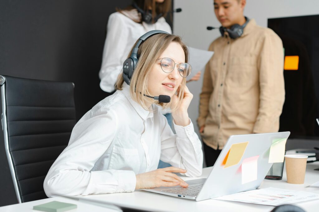 pexels-photo-7682103-7682103 Customer support professionals working with headsets and laptops in a modern office environment.