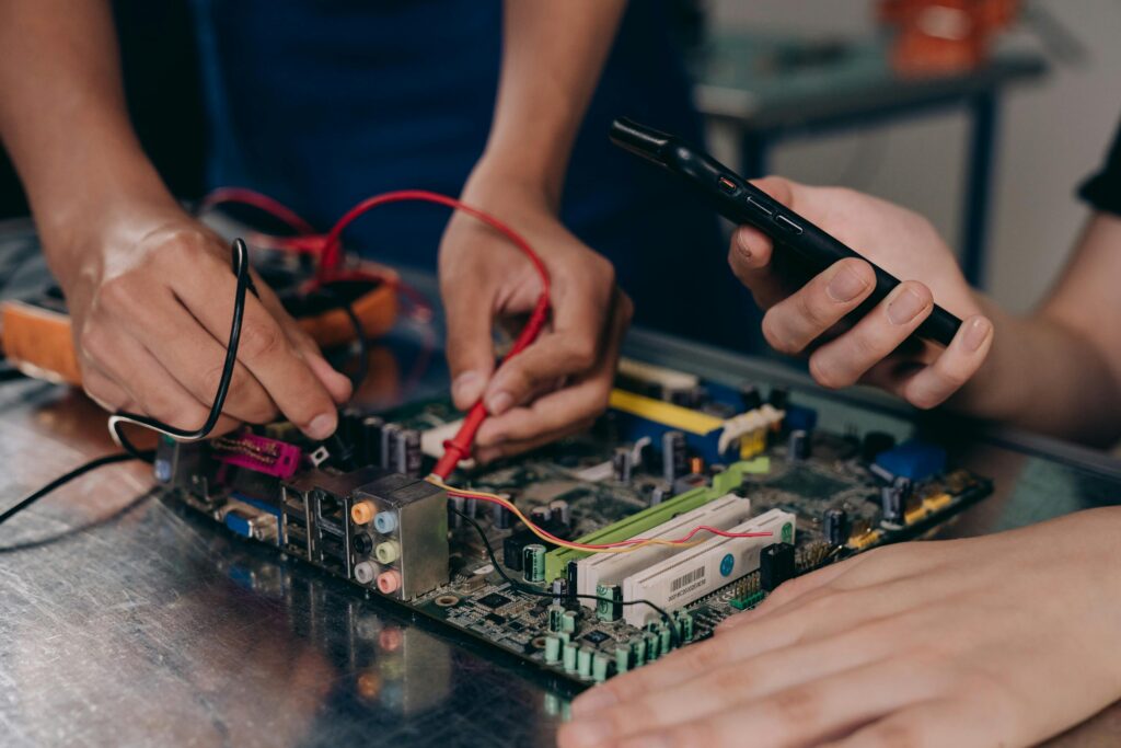 pexels-photo-9242887-9242887 Close-up of hands working on a motherboard using electrical tools and tester.