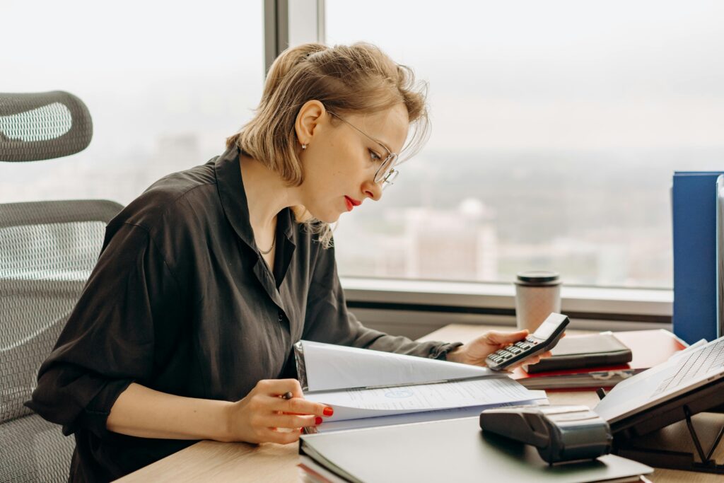pexels-photo-8297044-8297044 Woman accountant calculating financial documents at office desk.